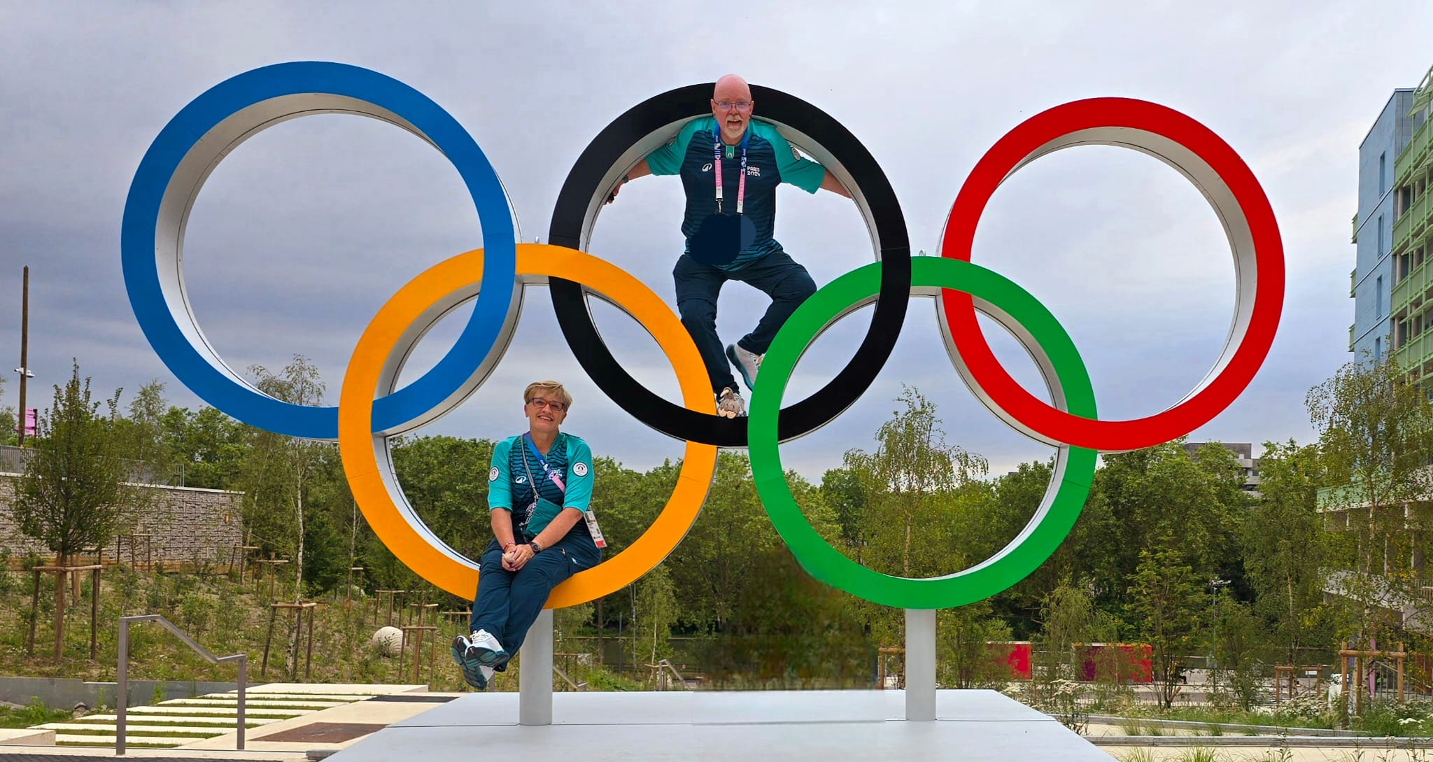 Two people sit in a giant statue of the Olympic rings